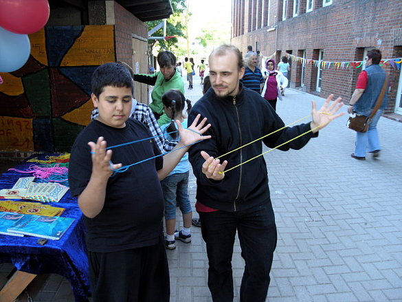 Auf dem Bild ist ein Kind und ein Erwachsener zu sehen, die alte Spiele ausprobieren. 