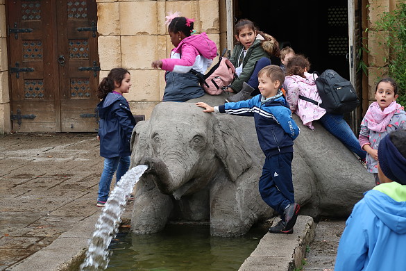Kinder sitzen auf einer Skulptur