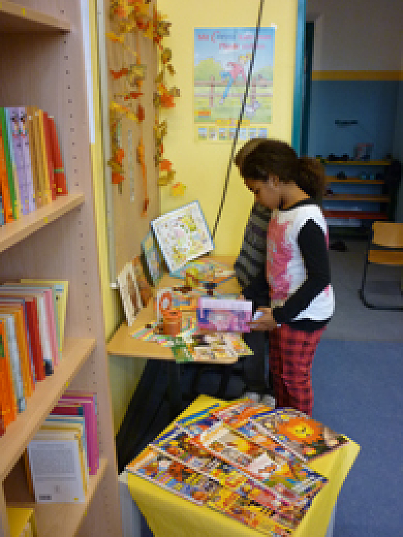 Ein Kind steht lesend vor einem Bücherregal.