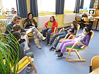Eine Gruppe Kinder sitzt in der Runde und liest gemeinsam ein Buch.