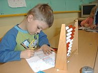 Ein Kind arbeitet mit einem Abakus.